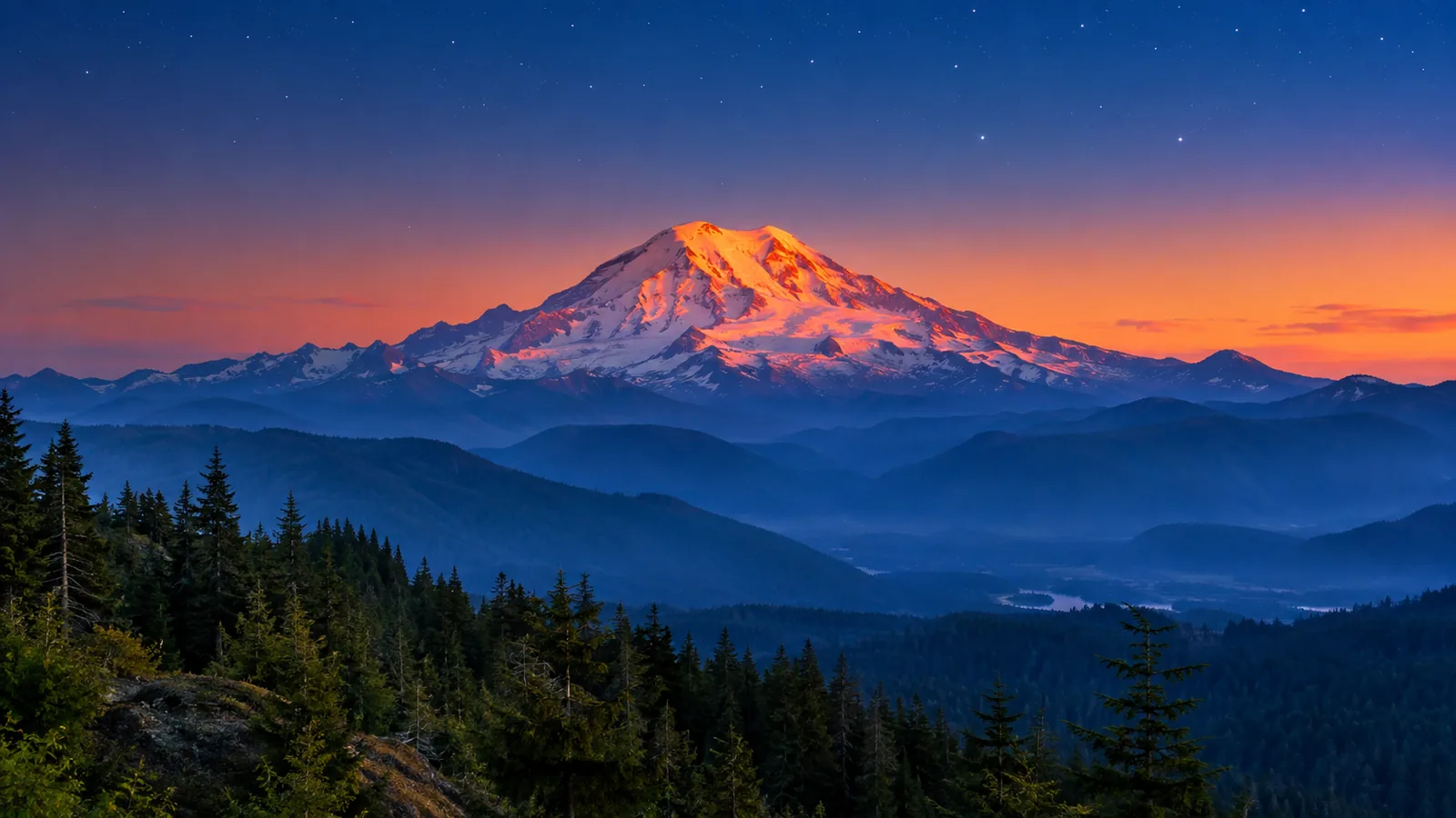 Mount Rainier im Alpenglühen über bewaldeten Graten in der Abenddämmerung